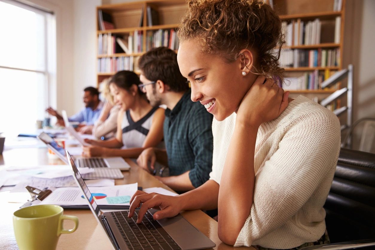 A group of people sitting at tables with laptops.